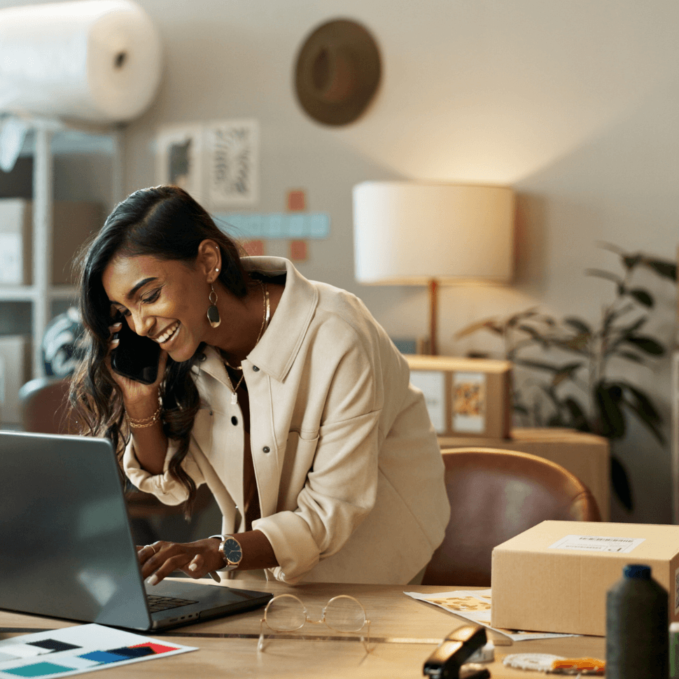 Woman in office on computer talking on phone