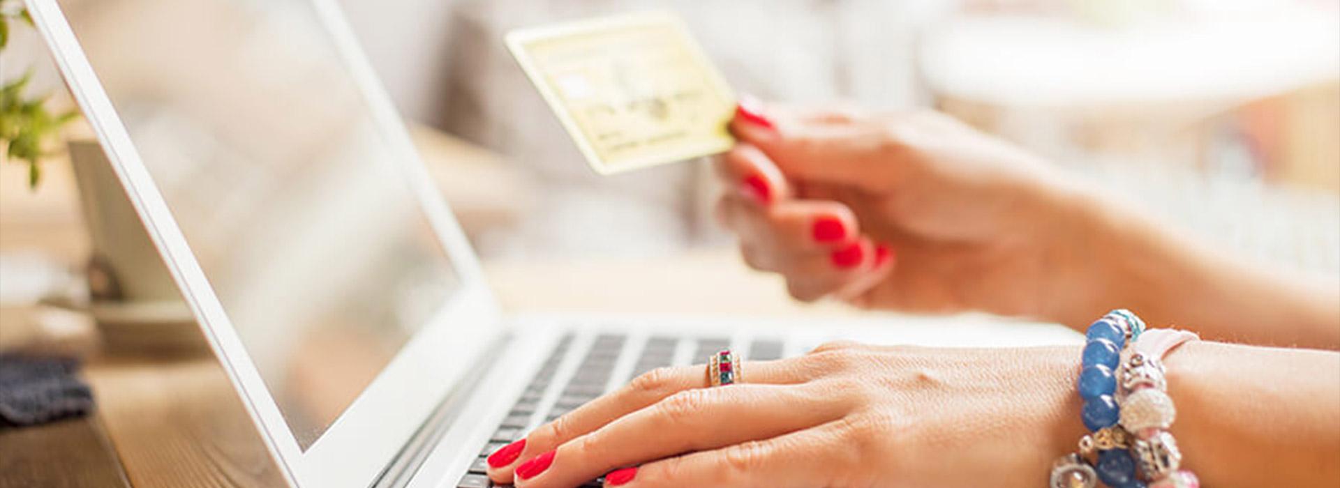 Hand holding credit card above laptop